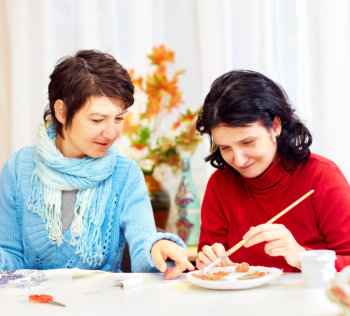 caregiver assisting woman in painting